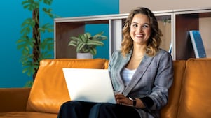 Person, die auf einer braunen Ledercouch mit einem Laptop sitzt