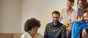 Fünf Menschen sitzen zusammengekauert in einem Büro