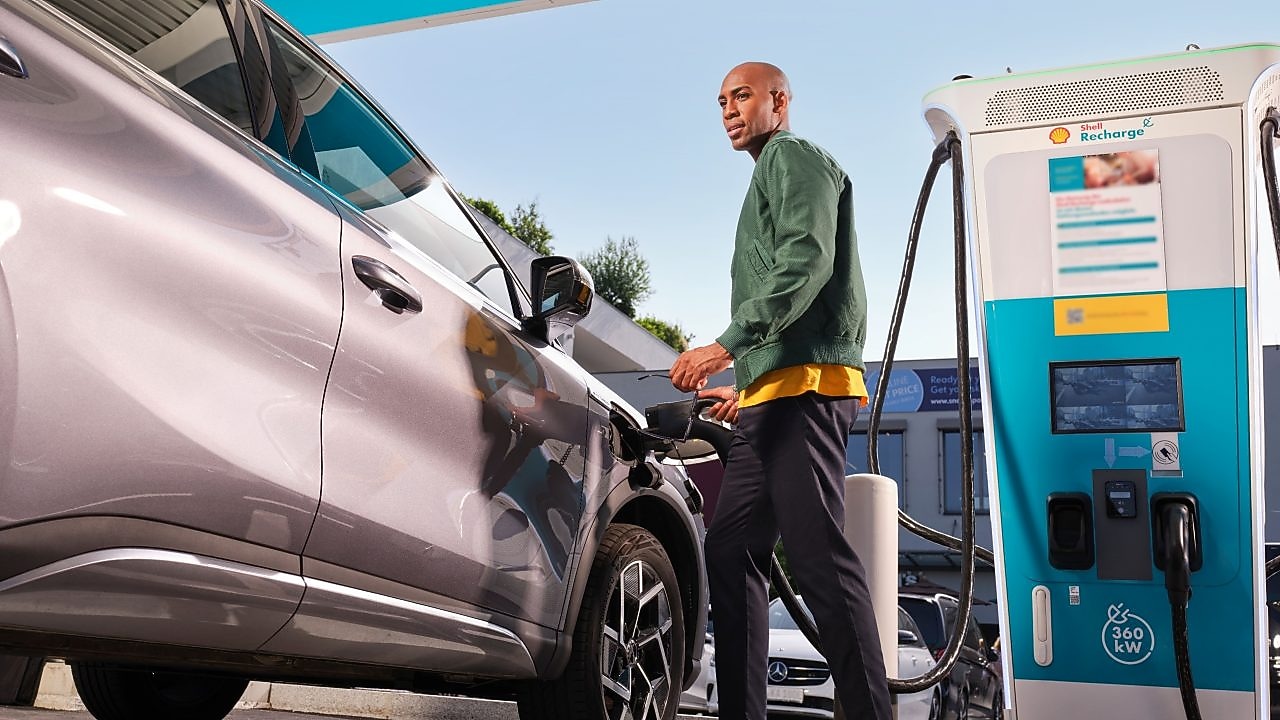 Person neben einer Shell Recharge Ladestation