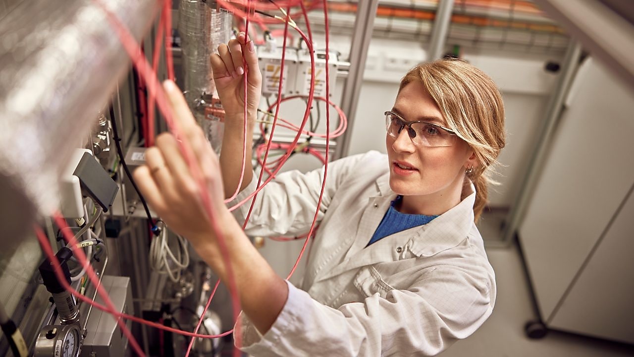 Person im Laborkittel bei der Arbeit mit einer Maschine