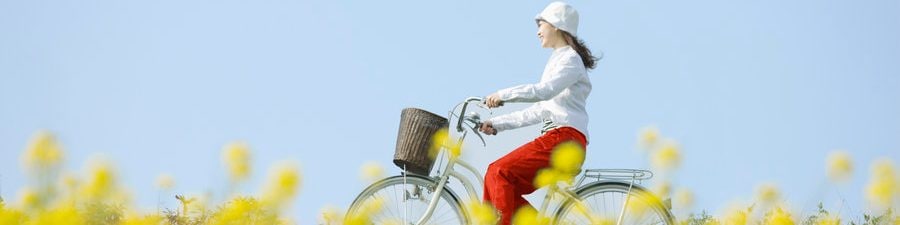Eine junge Frau fährt mit dem Fahrrad über eine sommerliche Blumenwiese