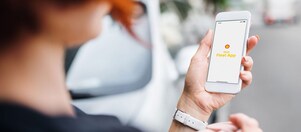 Eine Frau blickt auf ihr Smartphone mit der Shell Fleet App.