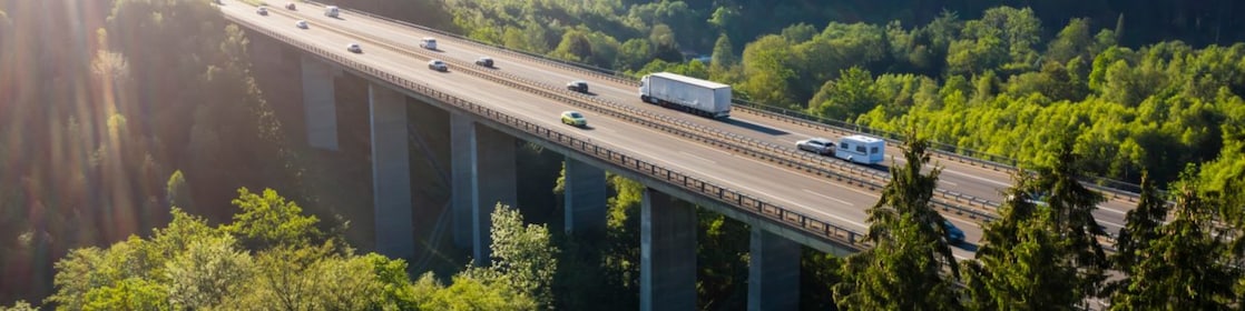 Fahrzeuge fahren auf einer Brücke im Grünen.