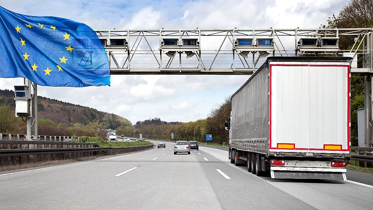 Eine Mautbrücke auf einer befahrenen deutschen Autobahn. Es ist eine Europa-Flagge zu sehen.