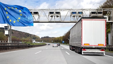 Eine Mautbrücke auf einer befahrenen deutschen Autobahn. Es ist eine Europa-Flagge zu sehen.