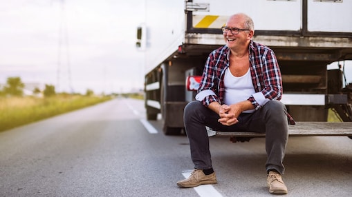 Ein Lkw Fahrer sitzt auf dem Heck seines Lkw.