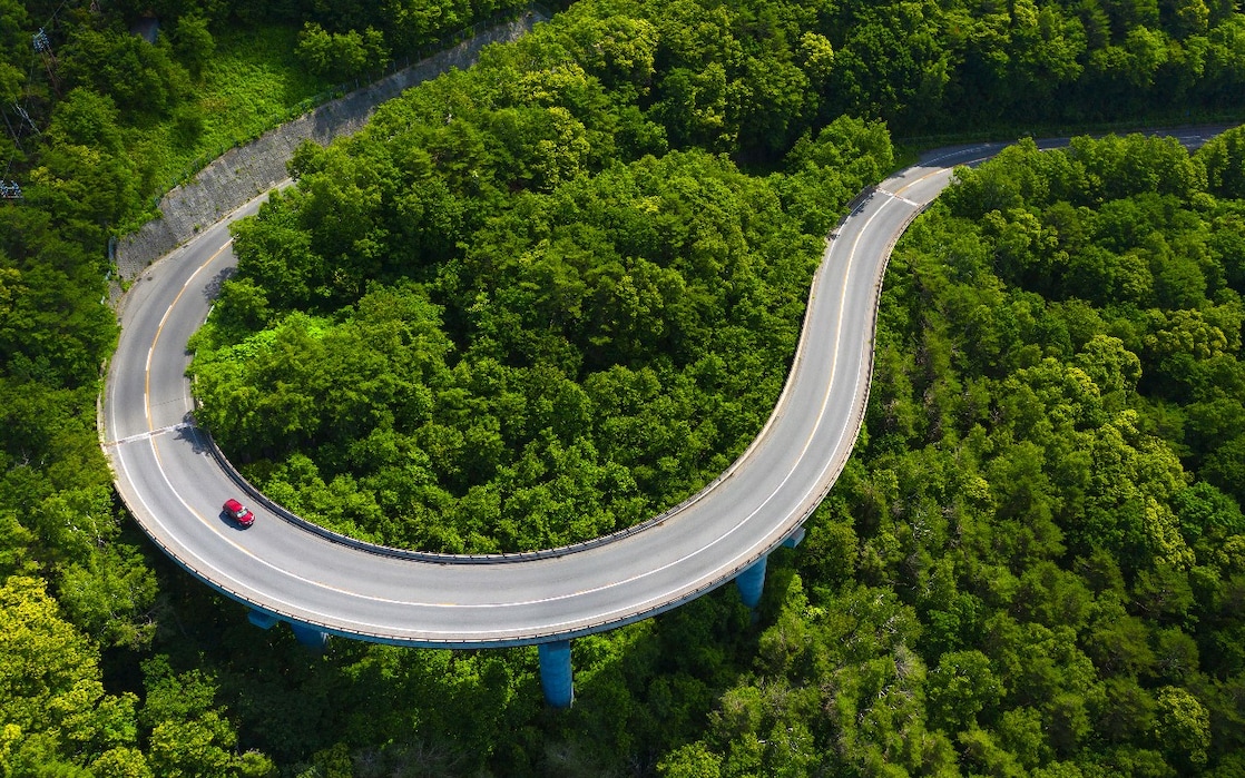 Ein Auto fährt auf einer Straße durch den Wald.