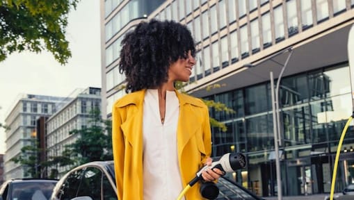 Frau schaut auf Kostenanzeige beim aufladen ihres Elektroautos