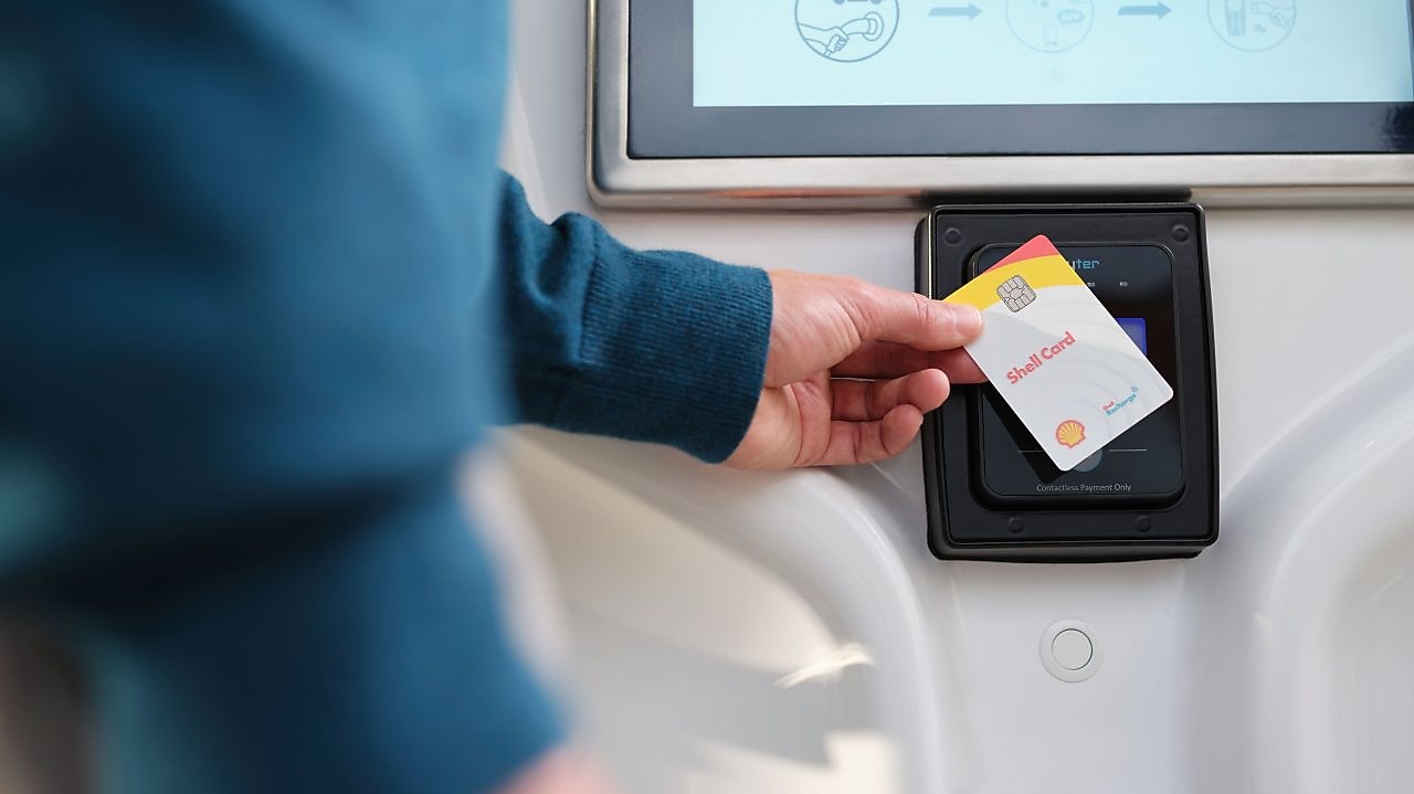 Die Shell Card wird über die Ladentheke gereicht.