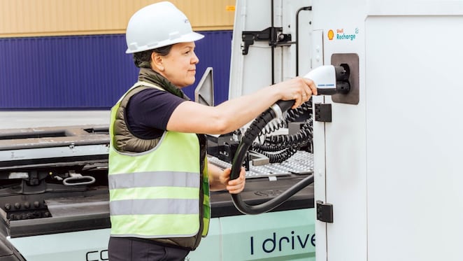 Lkw-Lenkerin steckt gerade den Ladestecher an einem Shell Recharge Ladedepot an.