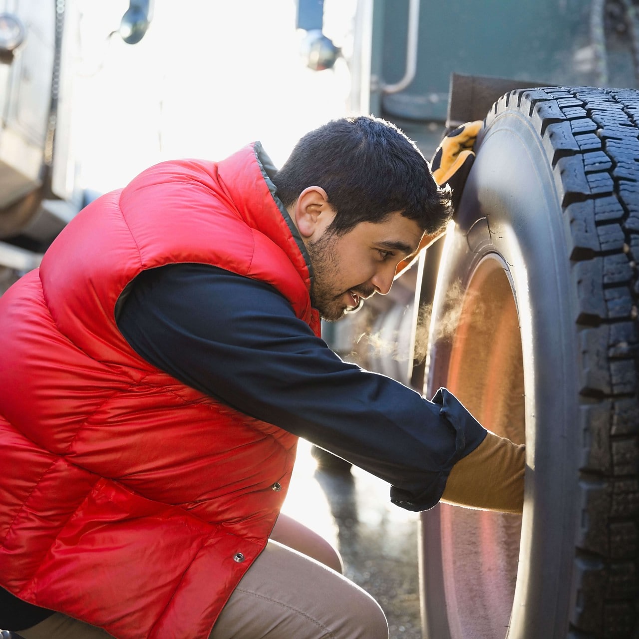Ein Lkw-Fahrer prüft den Reifen seines Lkw.