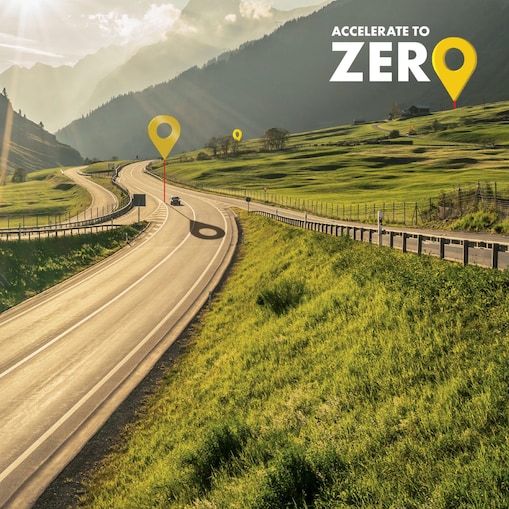 Auto fährt auf einer Schnellstraße durch grüne Landschaft mit Bergen im Hintergrund, Textaufschrift: "Accelerate to Zero".