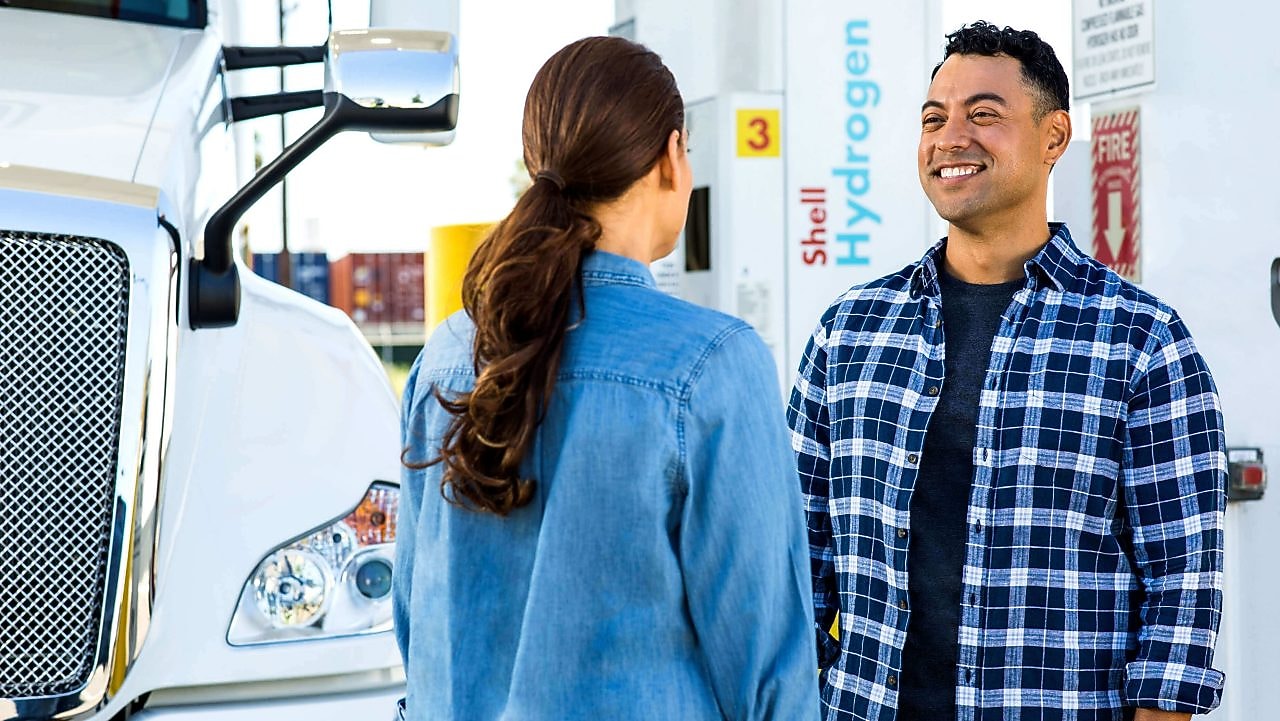 Ein junger Mann und eine junge Frau treffen sich an einer Shell Station.
