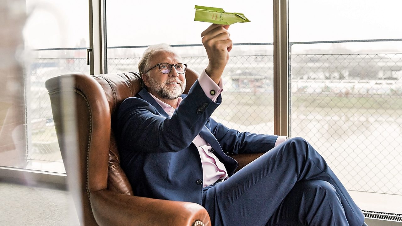 Mann mit Papierflieger sitzt in einem Sessel