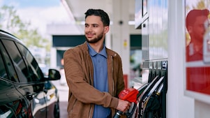 Junger Mann betankt sein Auto an einer Shell Station