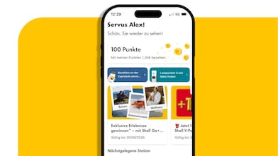 Smartphone mit geöffneter Shell App-Startseite, Begrüßung „Servus Alex!“, Anzeige von 100 Punkten und Teasern zu Shell Go+ Angeboten vor gelbem Hintergrund