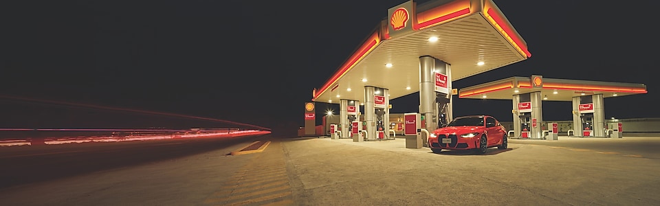 BMW M steht in der Nacht auf einer Shell Tankstelle