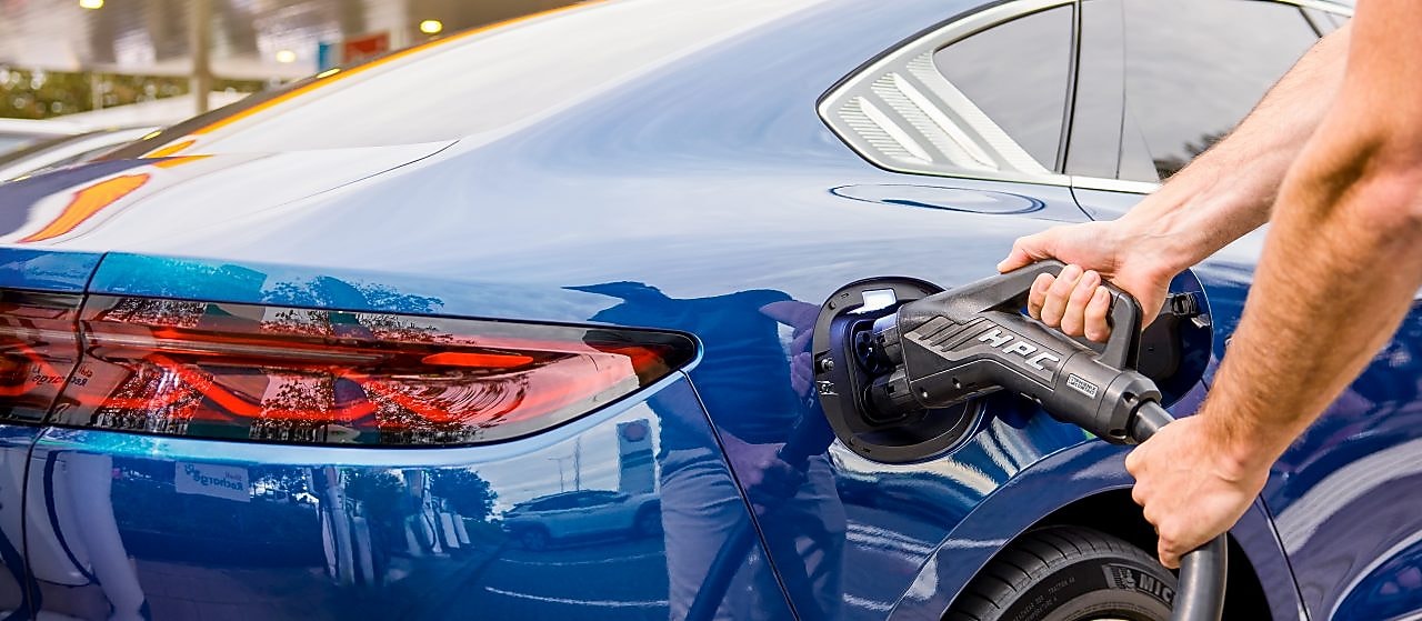 Driver is enjoying a coffee and using the Recharge App in their parked car at a Charge Point.