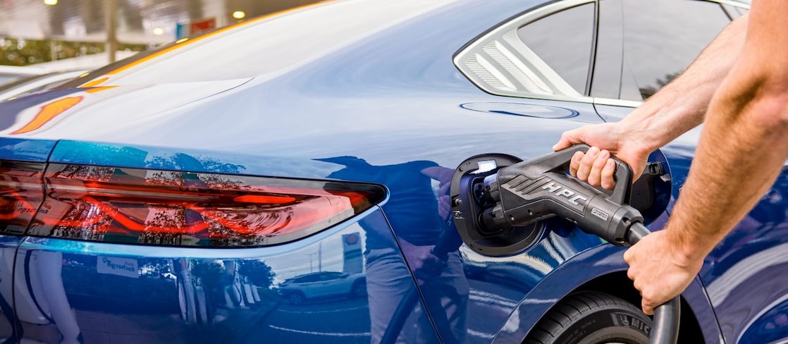 Driver is enjoying a coffee and using the Recharge App in their parked car at a Charge Point.