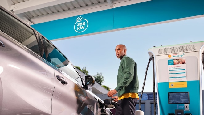 Lächelnde Frau lädt ihr E-Auto an einer Shell Recharge Ultraschnell-Ladesäule