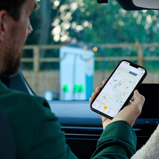 Eine Person nutzt die Shell App im Fahrzeug, um verfügbare E-Ladestationen auf einer Karte zu finden.