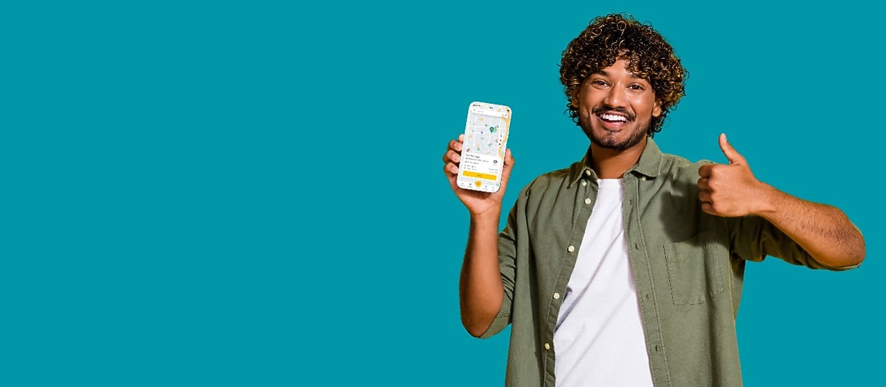 Lächelnder junger Mann mit der neuen Shell App auf dem Smartphone